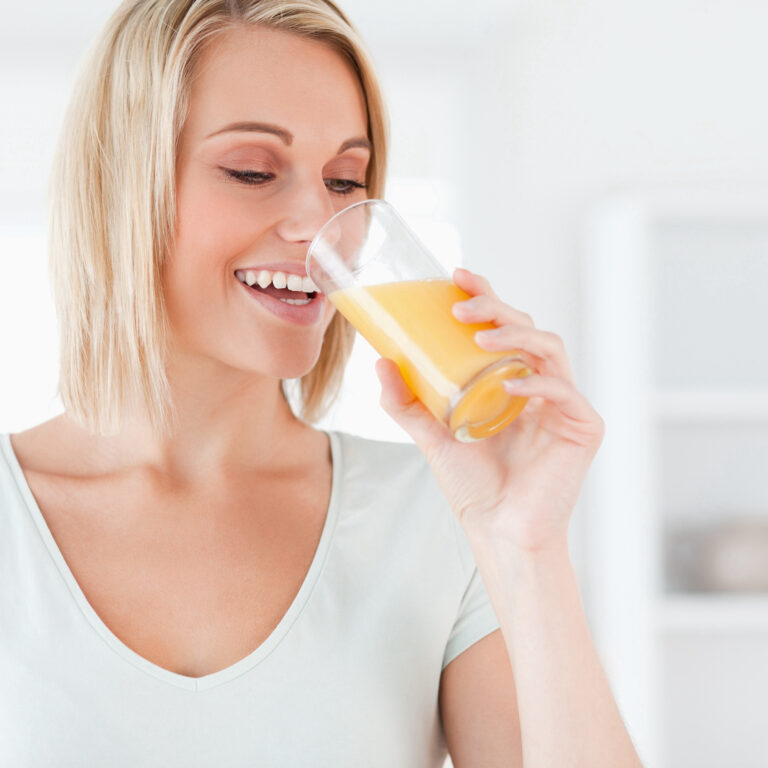 Smiling woman drinking orange juice